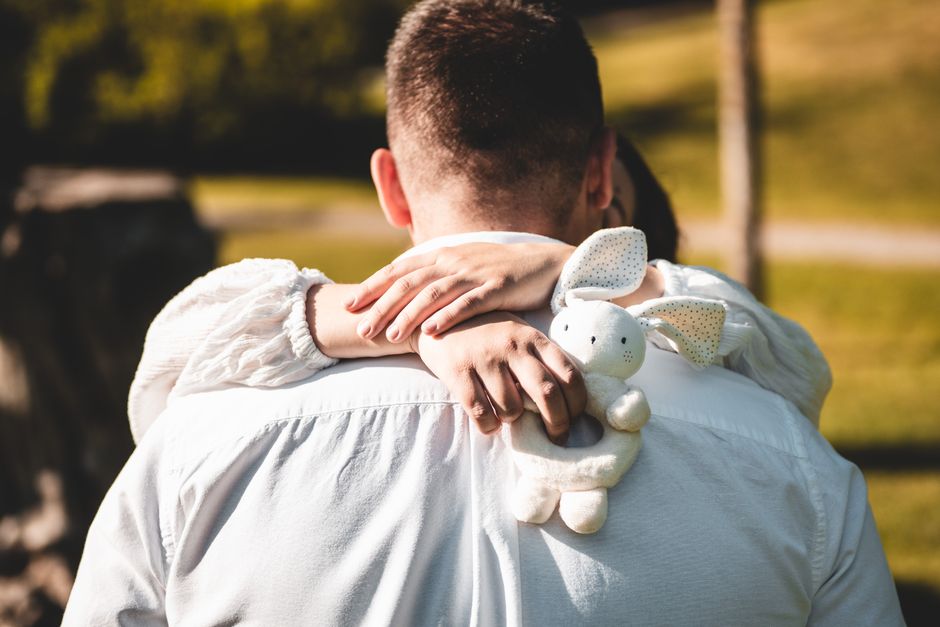 Heartwarming moment of a father carrying his child outdoors, featuring a plush bunny toy.