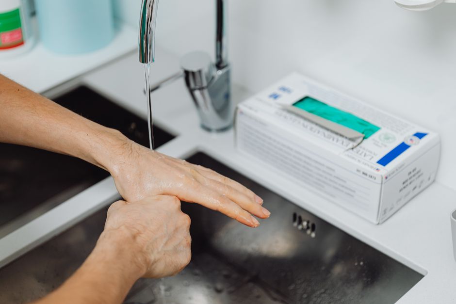 Detailed view of hand washing under running water for hygiene in a medical setting.