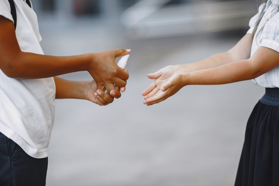 Close-up of hands sanitizing with a spray bottle, promoting hygiene and cleanliness.